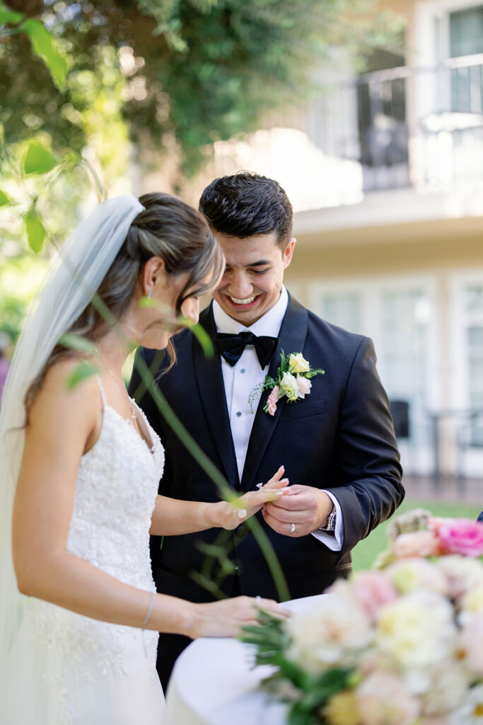 Bride and groom admiring the brides wedding ring as they sign their marriage certificate.