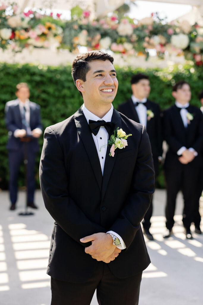 Groom smiling beneath a floral-covered pergola at the Hyatt Regency Newport Beach Amphitheater.