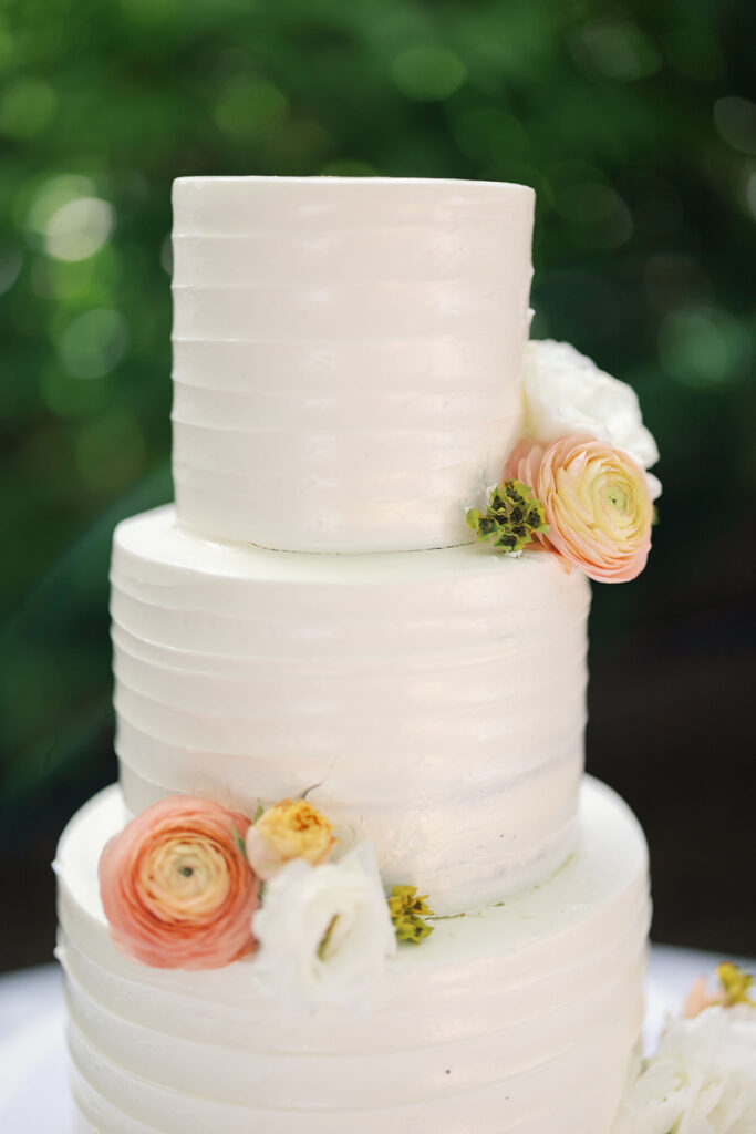 Three tiered white wedding cake with floral accents by Simply Sweet Cakery. 