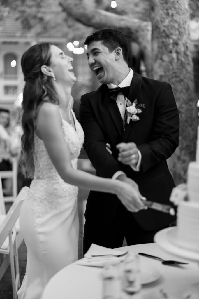 Couple laughing together while cutting their wedding cake at Hyatt Regency Newport Beach.