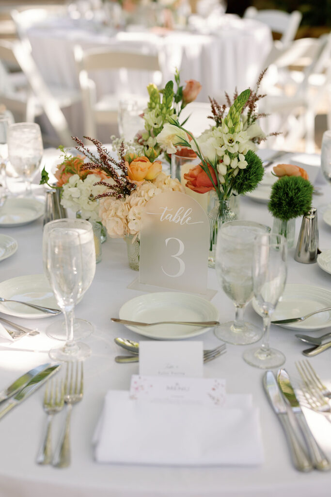 Outdoor wedding table with peach, orange, cream, and green floral centerpieces at Hyatt Regency Newport Beach.