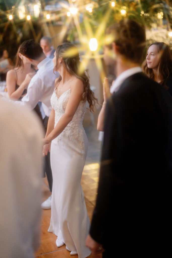 Bride dancing with guests beneath glowing string lights at a Newport Beach hotel wedding.