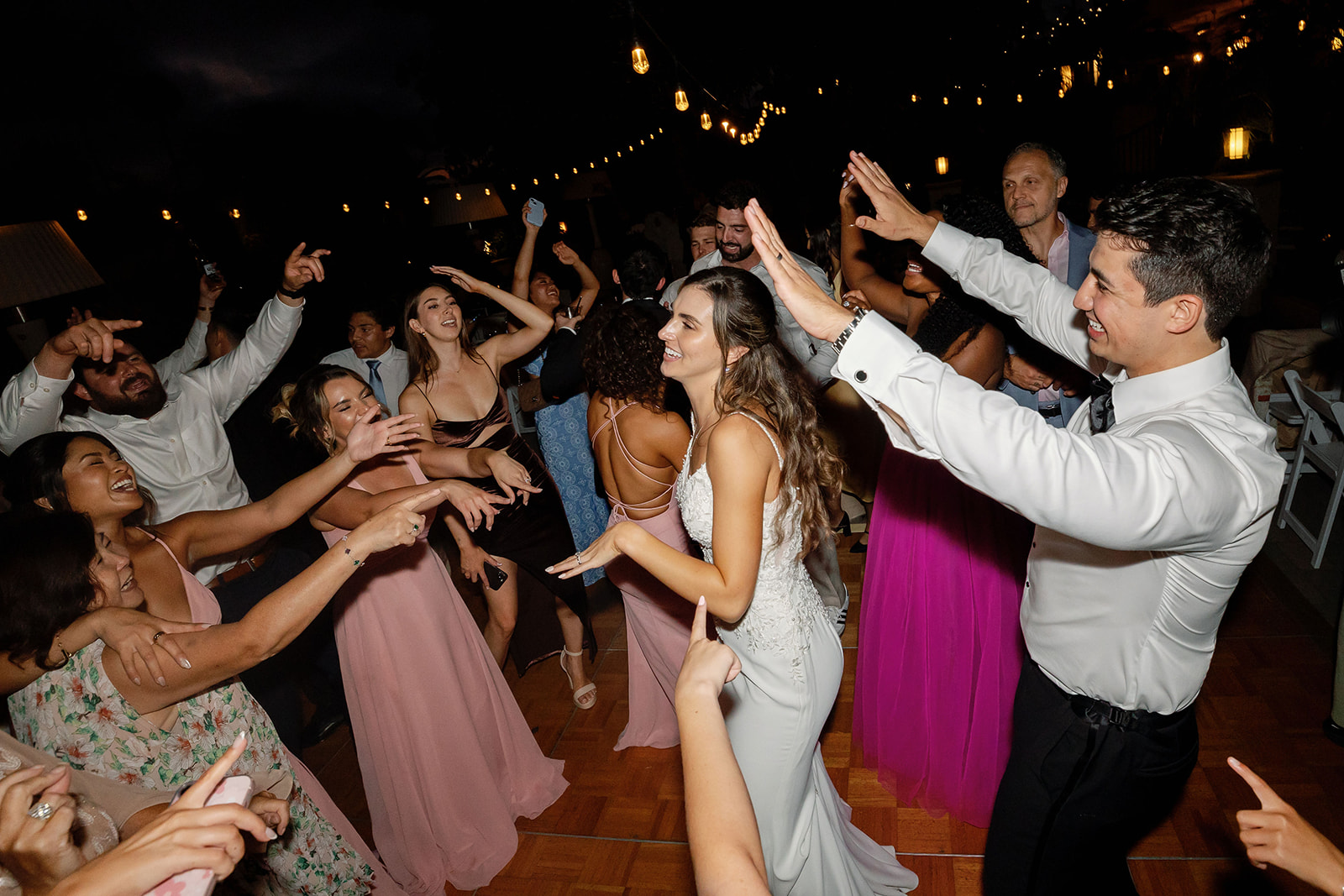 Bride dancing with guests while the groom cheers her on at Hyatt Regency Newport Beach.
