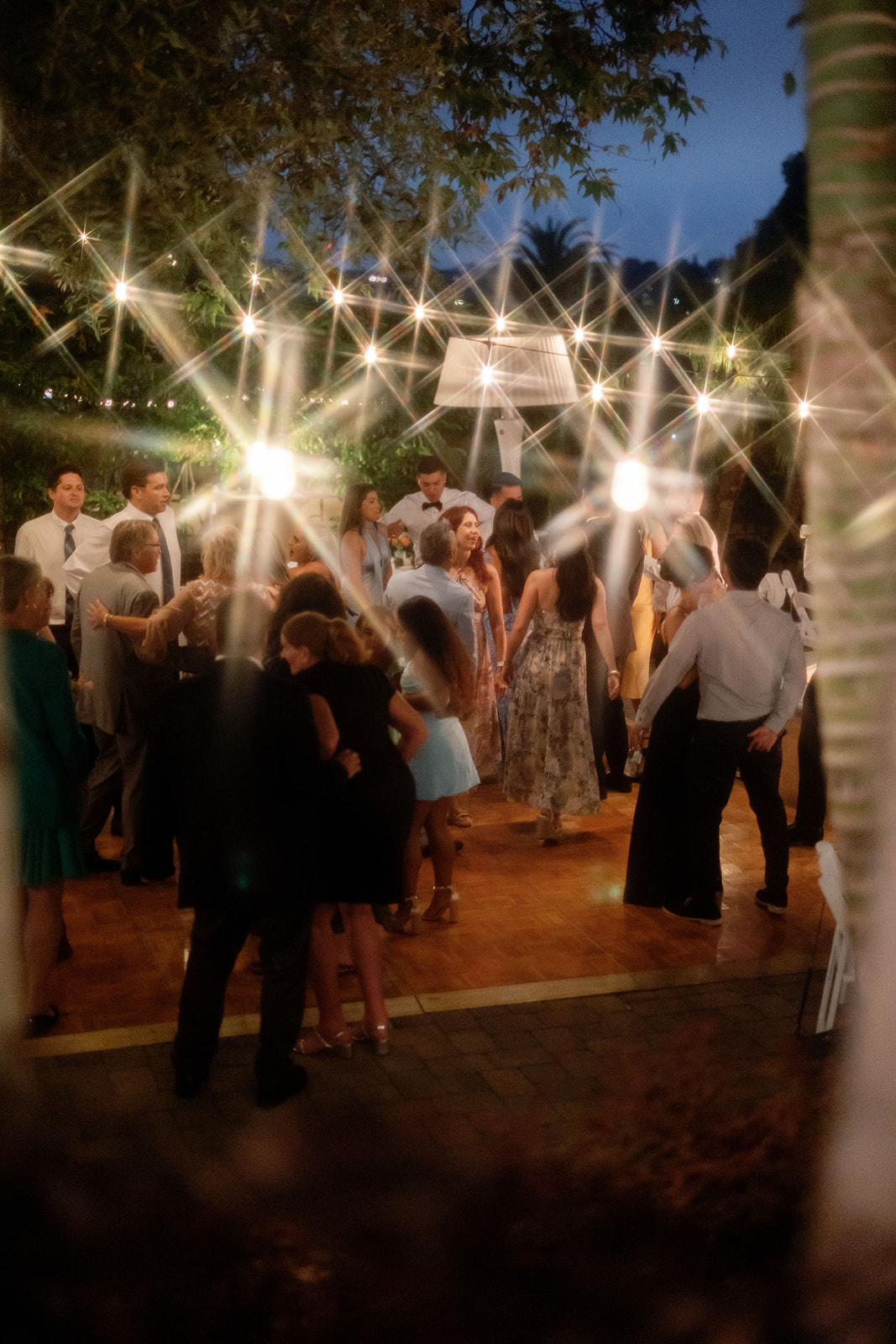 Wedding guests filling the outdoor dance floor beneath string lights in the Garden.