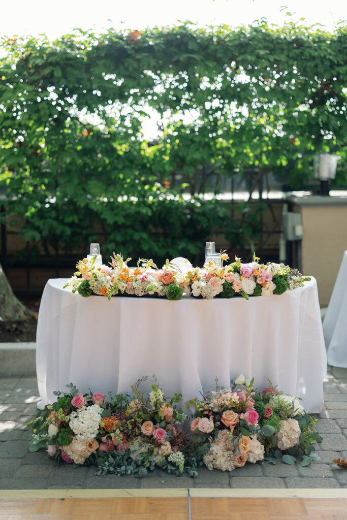 Sweetheart table surrounded by colorful flowers in the Garden at Hyatt Regency Newport Beach.