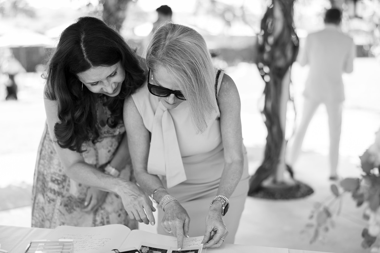 Wedding guests looking at photos and handwritten messages of a guest book during cocktail hour.