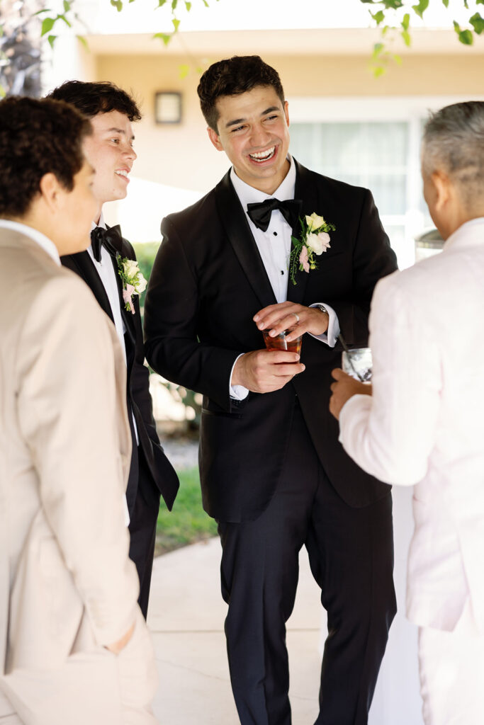 Groom laughing with guests during an outdoor Hyatt Regency Newport Beach wedding cocktail hour.