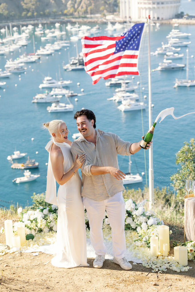 Couple popping champagne during their Catalina Island proposal at Buena Vista Point. 