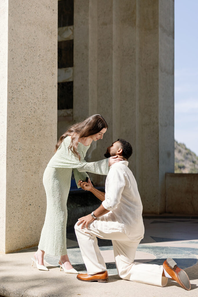 Woman leaning down to lovingly touch her fiancé during their proposal.