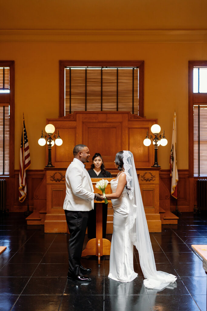 Bride and groom holding hands during their intimate Old Orange County Courthouse wedding ceremony in the Historic Room.