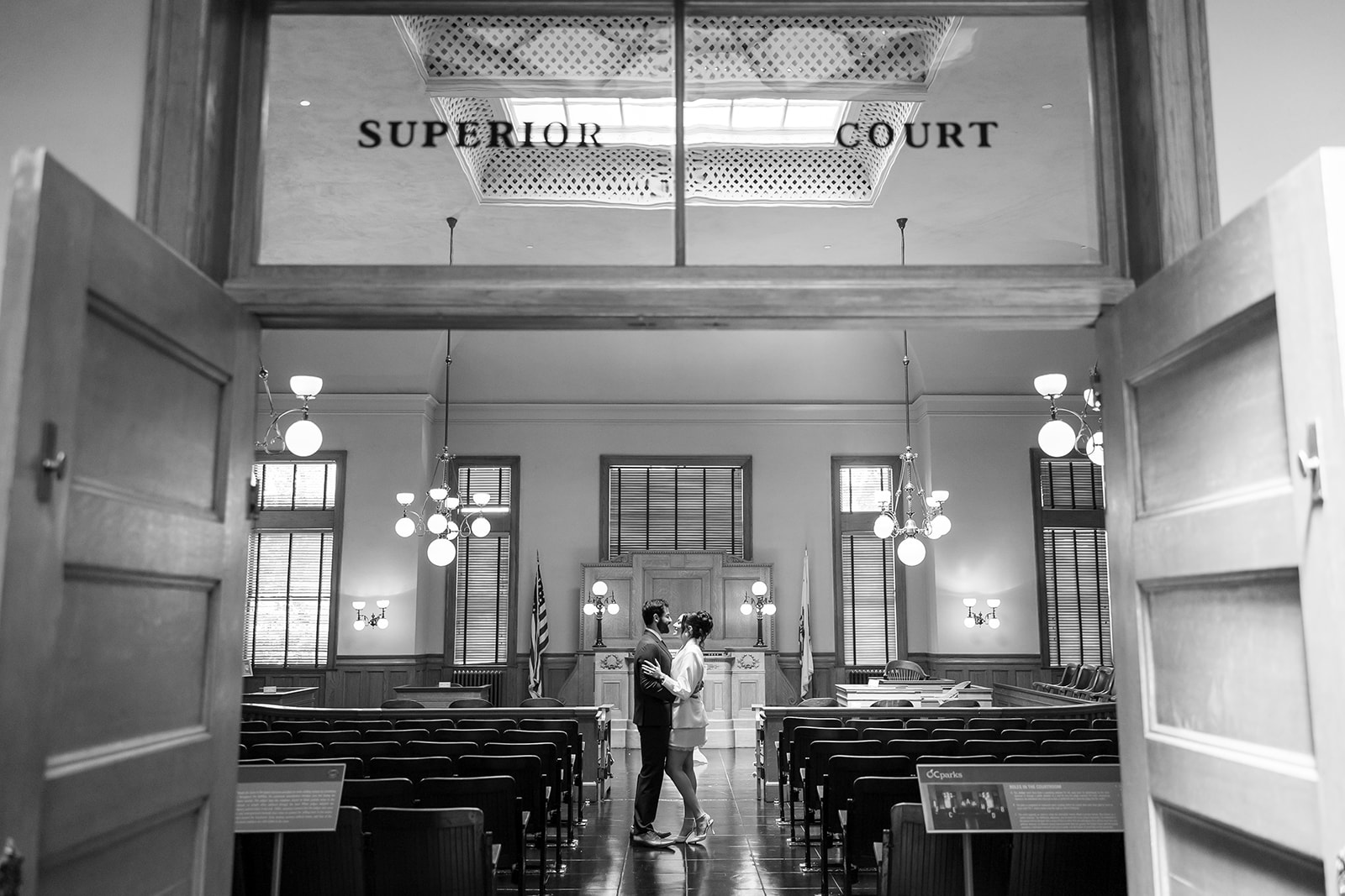 Black and white photo of a bride and groom standing in the Historic Room for their Old Orange County Courthouse wedding in Santa Ana, California.