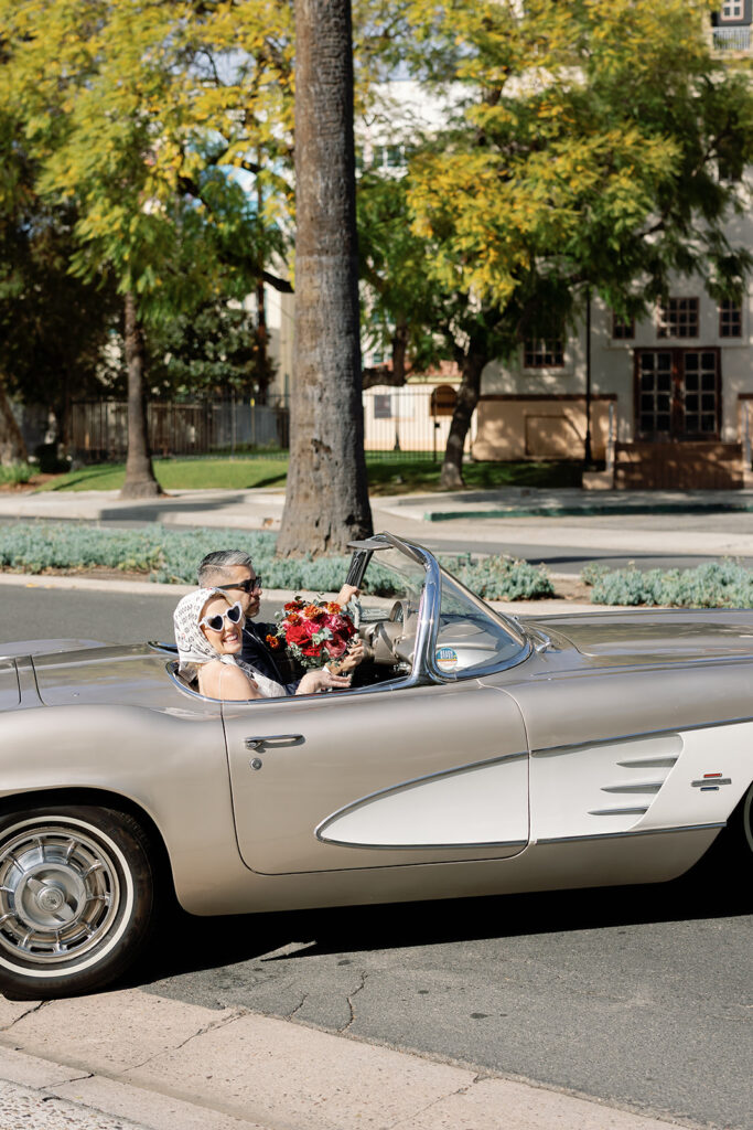 Bride and groom riding off in a classic car.