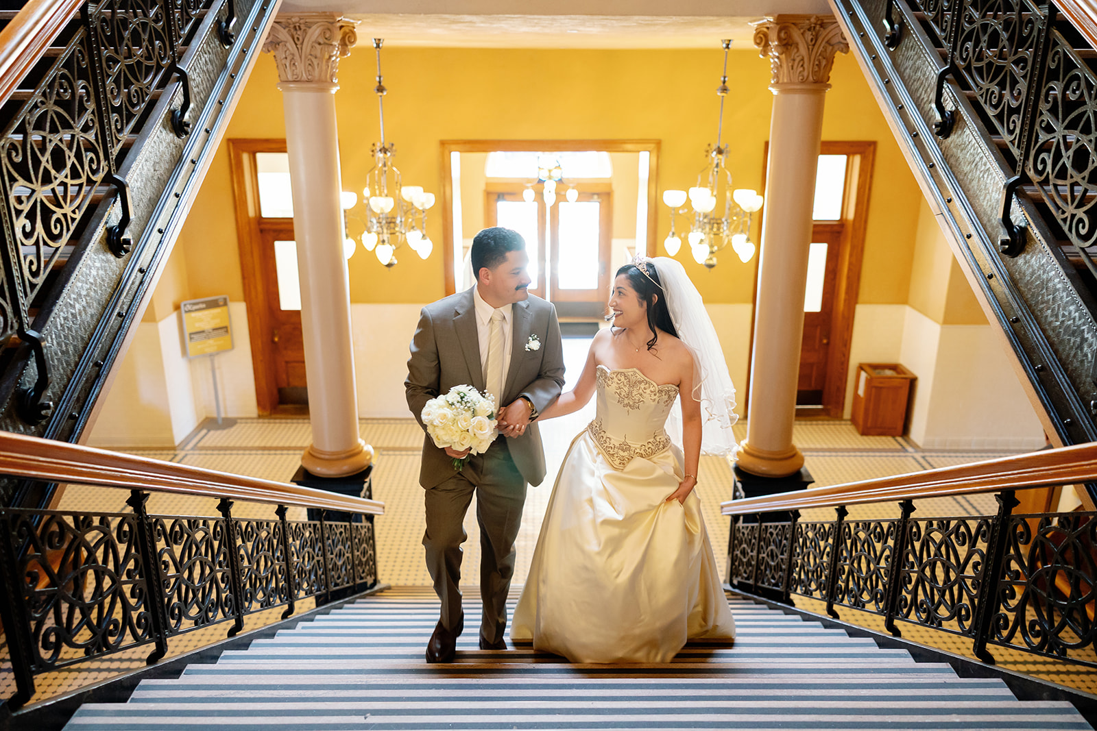 Bride and groom walking up the indoor steps at Old Orange County Courthouse in Santa Ana, California.