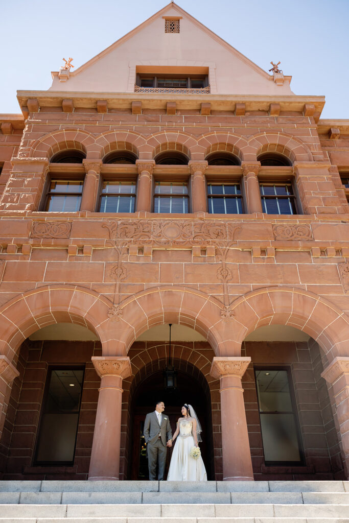Bride and groom posing outside of the  Old Orange County Courthouse in Santa Ana, California.