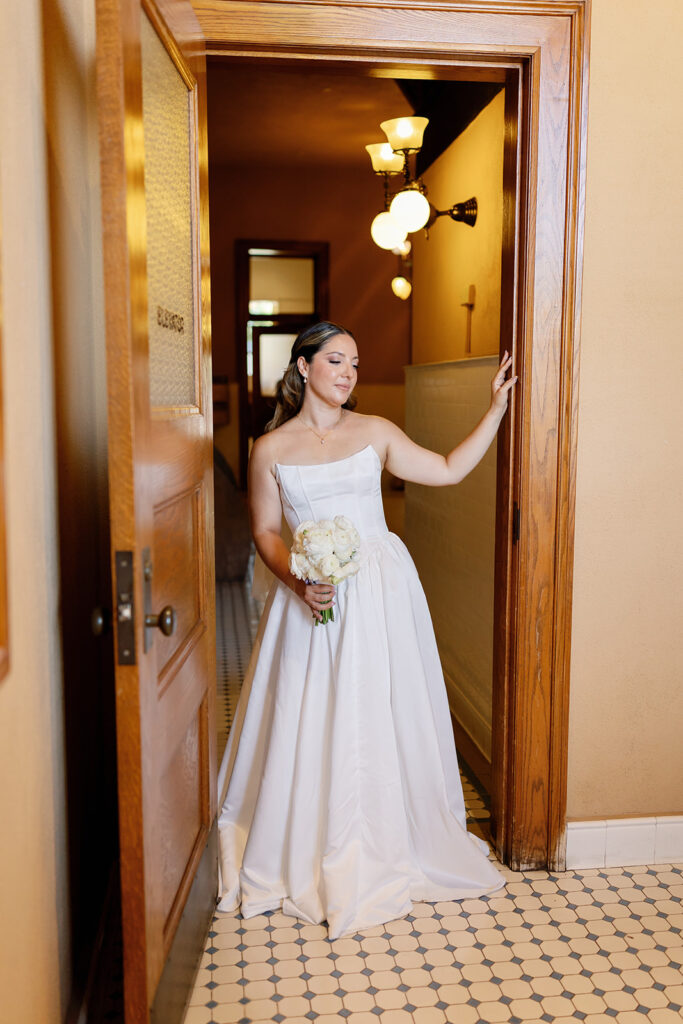 Bride posing near a doorway for their bridal portraits inside the Old Orange County Courthouse in Santa Ana, California.