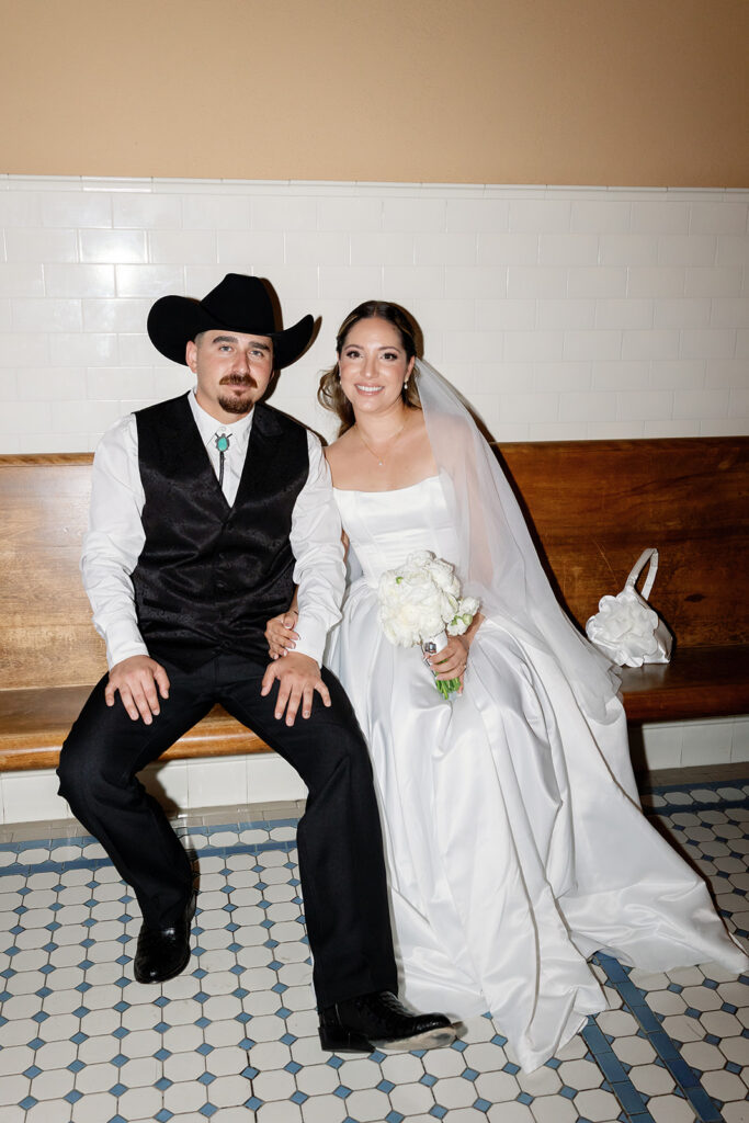 Bride and groom sitting on a bench during their Old Orange County Courthouse wedding photos in Santa Ana, California.