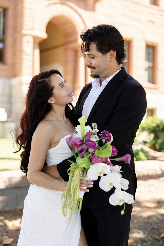 Bride and groom posing in front of the the Old Orange County Courthouse in Santa Ana, California.