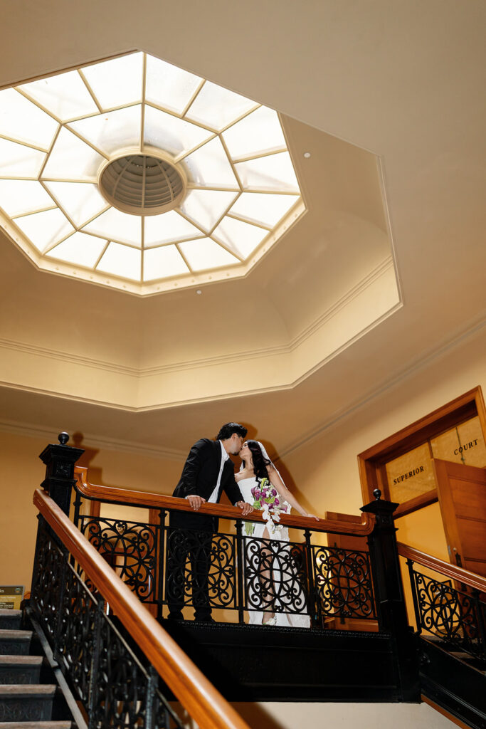 Bride and groom kissing inside the Old Orange County Courthouse for their wedding photos in Santa Ana, California.