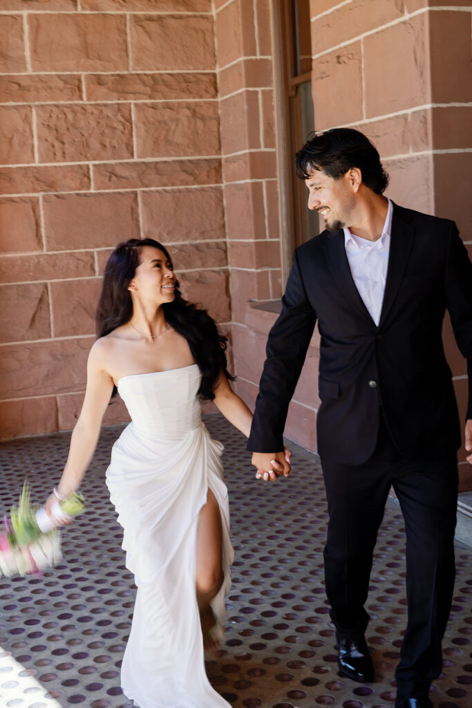 Bride and groom walking outside of the Old Orange County Courthouse in Santa Ana, California together.