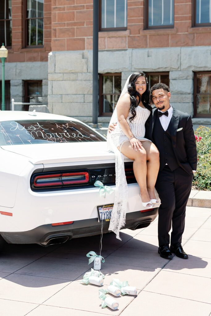 Bride and groom posing with a car in front the Old Orange County Courthouse in Santa Ana, California.