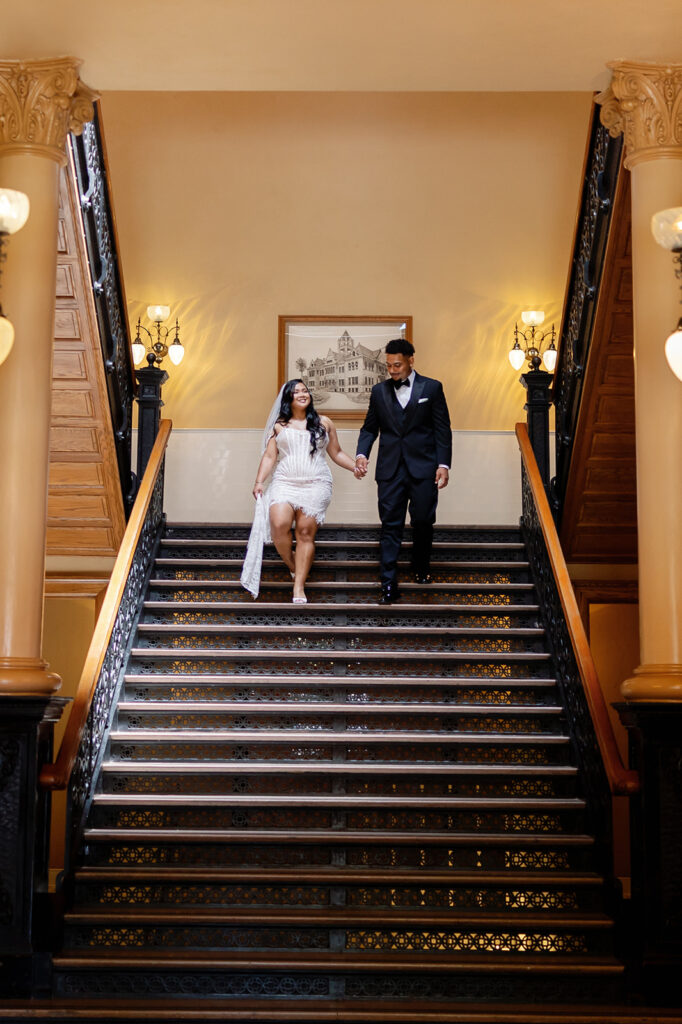Bride and groom walking down the stairs at Old Orange County Courthouse in Santa Ana, California.