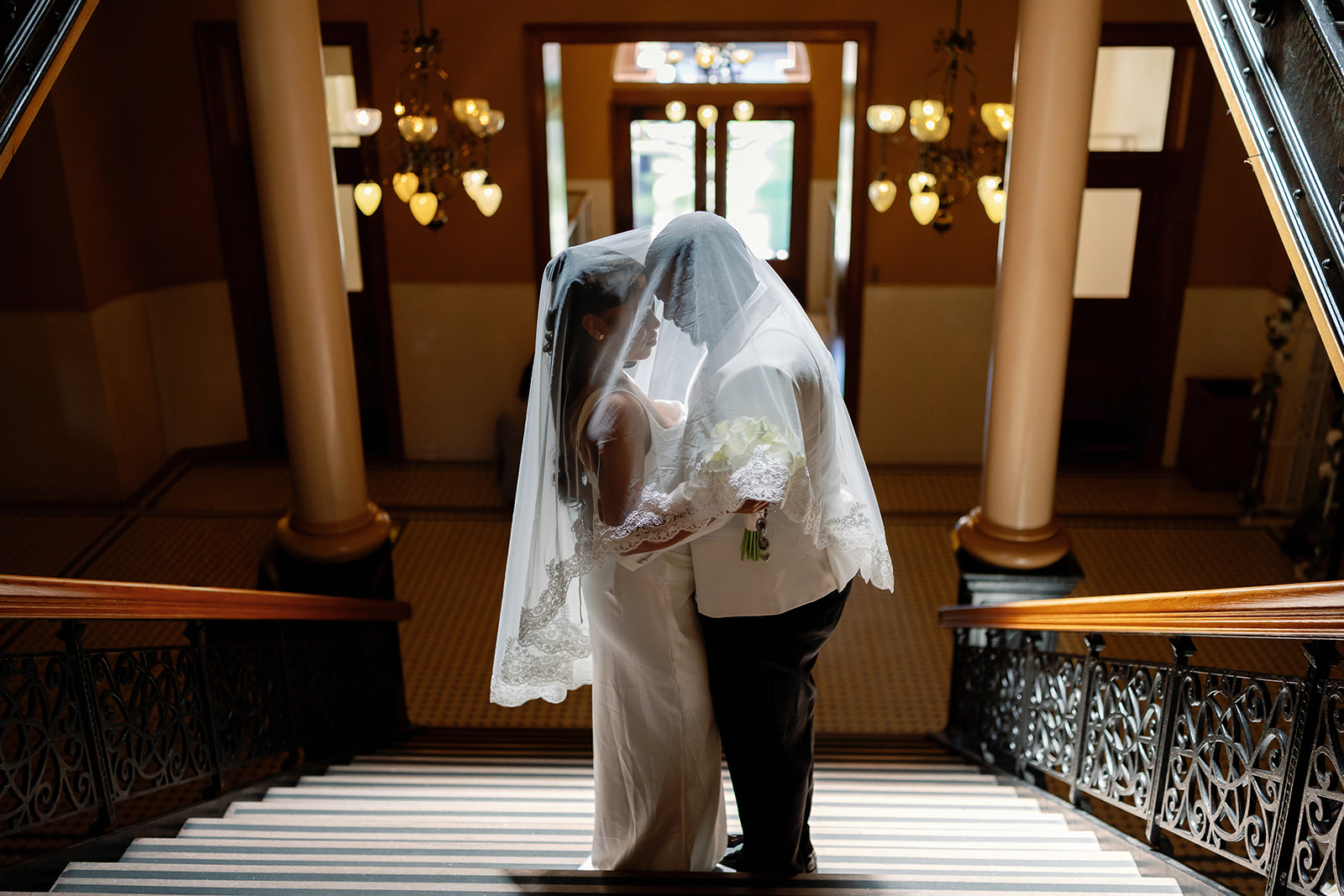 Bride and groom posing on the staircase for their Old Orange County Courthouse wedding in Santa Ana, California.