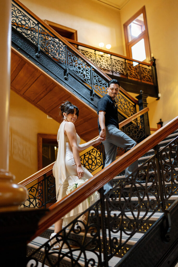 Bride and groom walking up the stairs for their Old Orange County Courthouse wedding photos in Santa Ana, California.