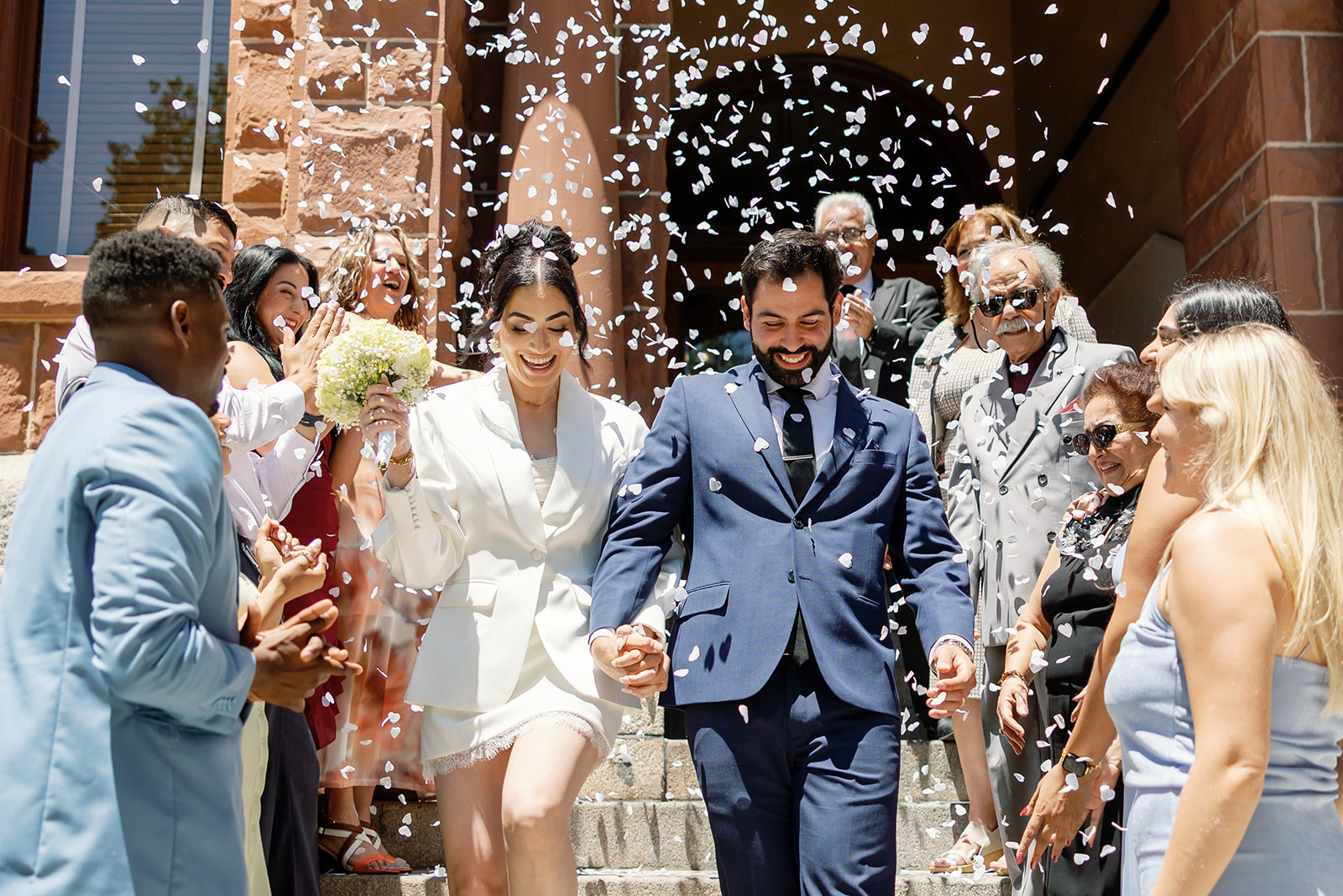Bride and groom walking back down the steps with a petal toss after their Old Orange County Courthouse wedding in Santa Ana, California.