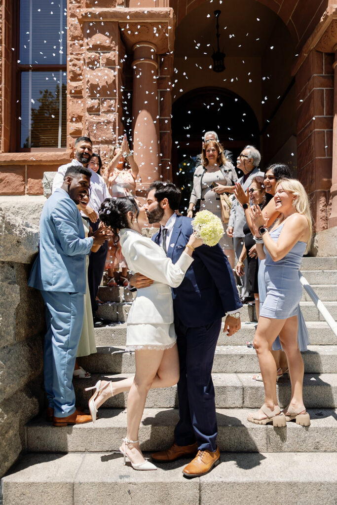 Bride and groom kissing after a petal toss.